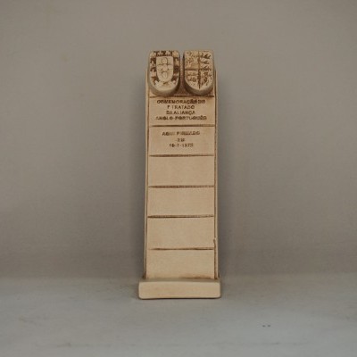 Expositor de madeira clara com ganchos metálicos e texto impresso, sobre fundo cinza claro