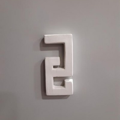 Objeto branco de cerâmica geométrico na parede cinzenta