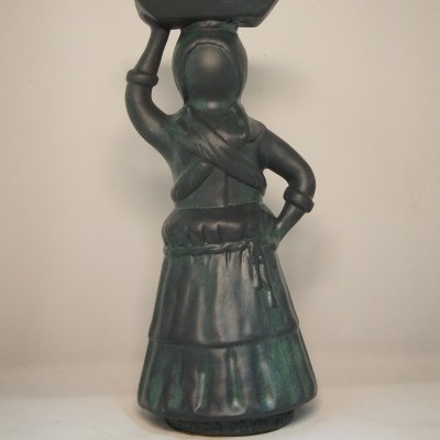 Escultura decorativa de mulher segurando bandeja na cabeça, em tons de verde e preto