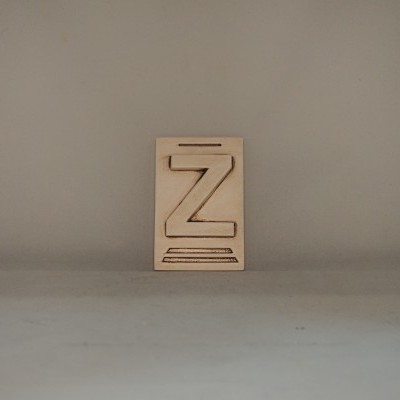 Placa de madeira clara com letra 'Z' recortada em relevo