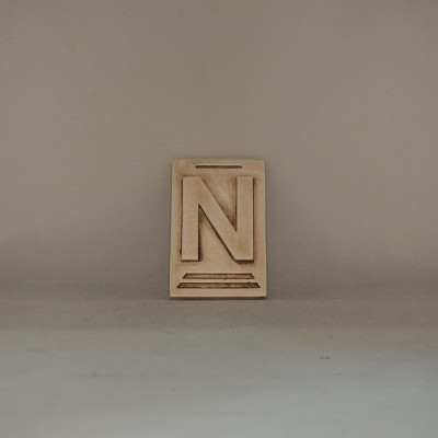 Bloco pequeno bege com letra N em relevo