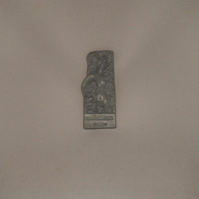 Objeto metálico decorado em relevo com texto SOLID BRONZE