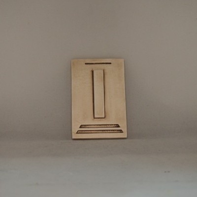 Placa decorativa castanha clara com relevo geométrico sobre fundo cinzento