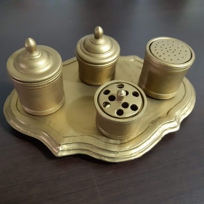 Conjunto dourado de recipientes metálicos com tampa sobre prato