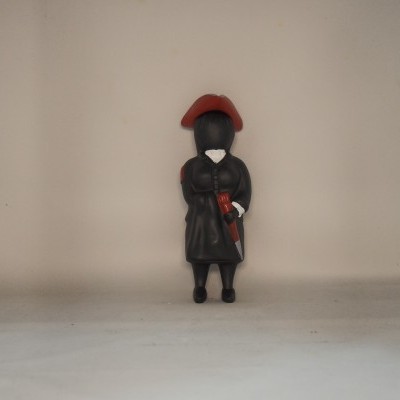 Figura decorativa preta com chapéu vermelho e faca