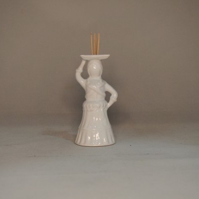 Figurinha decorativa em cerâmica branca com palitos de incenso.