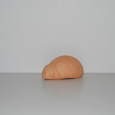 Pequena escultura de pedra alaranjada com textura lisa em fundo cinzento