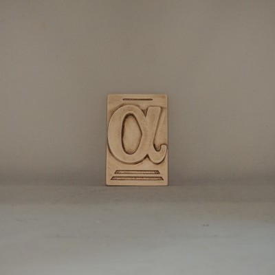 Bloco de madeira com símbolo alfa recortado