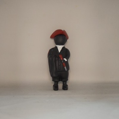 Figura decorativa preta com roupa e boina vermelha em fundo claro