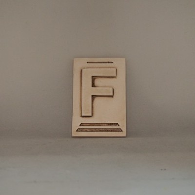 Placa de madeira clara com a letra F em relevo