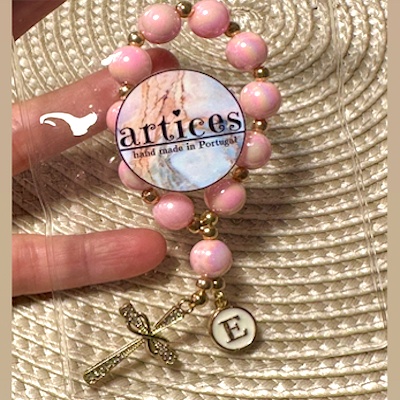 Pulseira rosada com medalhas e texto 'artices hand made in Portugal'