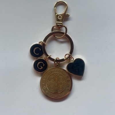 Chaveiro dourado com pendentes em forma de coração, moedas e letras C e G