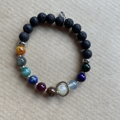 Pulseira de contas coloridas e negras sobre fundo bege texturizado