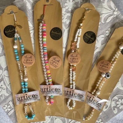 Quatro pulseiras coloridas em cartões de papel kraft com etiquetas em fundo texturado branco