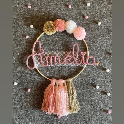 Circular decorativo com o nome Amélia em fio rosa e pompons coloridos