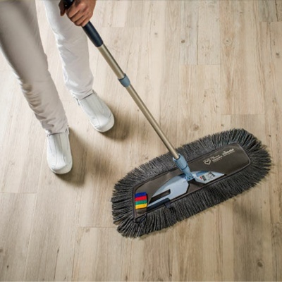 Mopa retangular cinza escuro com franjas negras num chão de madeira clara