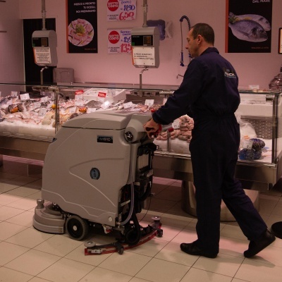 Homem a limpar o chão com máquina limpa-pavimentos num supermercado de peixe