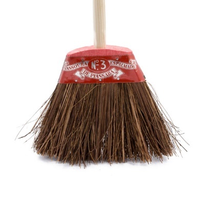 Vassoura com cerdas castanhas e suporte vermelho com texto, cabo de madeira.