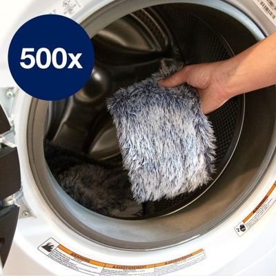 Mão a colocar pano felpudo azul e cinza dentro de máquina de lavar roupa branca