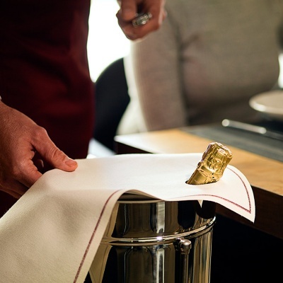 Champanheira metálica com garrafa de champanhe e toalha branca ao lado de mesa