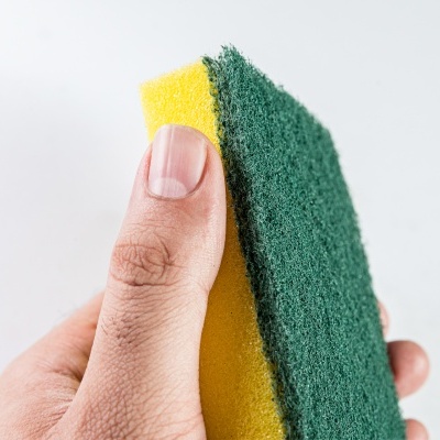 Esponja de cozinha amarela e verde segurada por mão