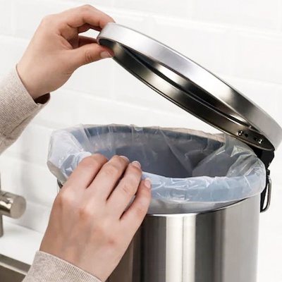 Lixeira de cozinha em inox com saco plástico junto a pia.