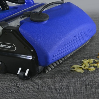 aspirador compacto azul e preto com escova e resíduos amarelos sobre tecido cinzento