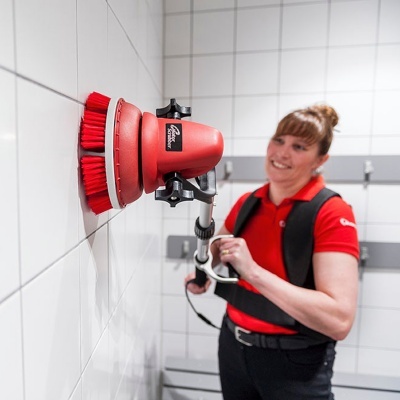 Mulher a limpar azulejos com escova elétrica vermelha da marca Caroline