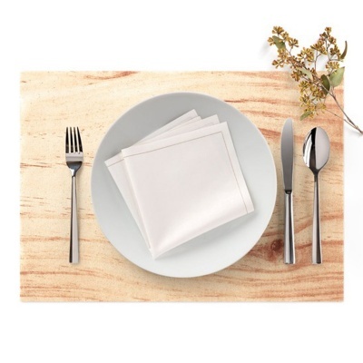 Conjunto de talheres em aço inoxidável com prato branco e guardanapos sobre placemat de madeira clara