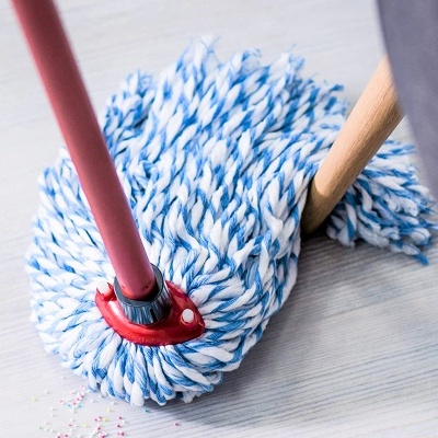 esfregão azul e branco com pega vermelha e cabo vermelho numa superfície clara