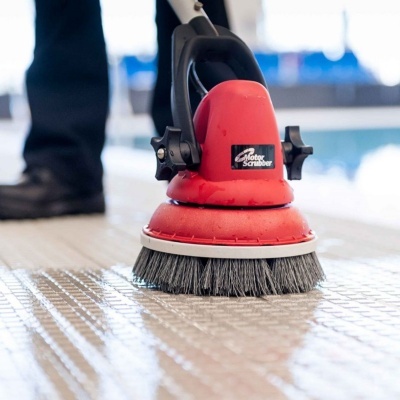 Escova elétrica de limpeza vermelha e preta a limpar ladrilhos