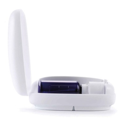 Dispositivo branco com tampa aberta mostrando um frasco roxo e compartimento