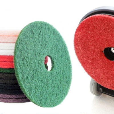 Discos abrasivos coloridos com um disco vermelho montado numa máquina polidora preta