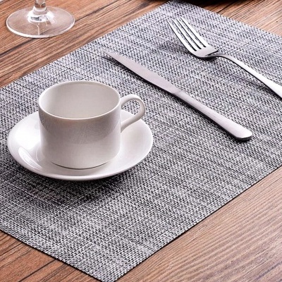 Conjunto de chávena e pires branco numa mesa com individual cinza e talheres