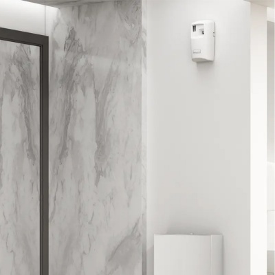 Dispensador de sabão branco montado na parede em casa de banho com azulejos de padrão mármore e espelho com moldura preta