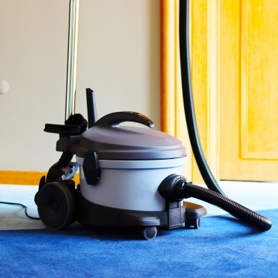 aspirador de pó cinza e preto com mangueira flexível sobre tapete azul