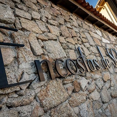 Placa metálica preta com texto em parede de pedra rústica clara