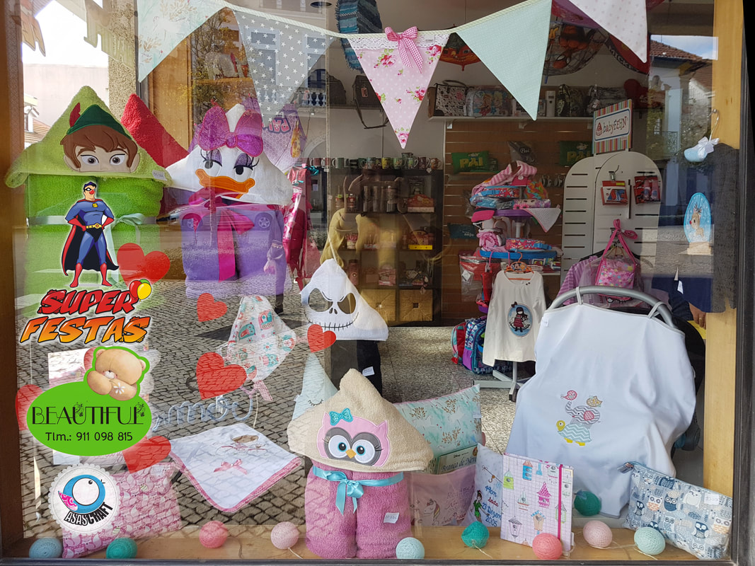 Vitrine de loja com almofadas infantis, peluches e roupas expostas.