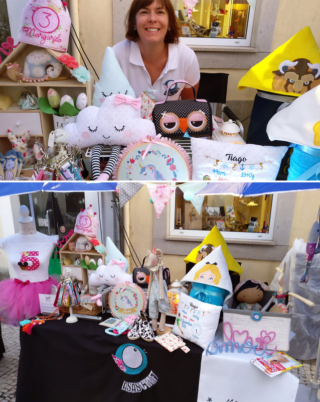 Festival Internacional de Marionetas de Ovar 2017 Mesa com artigos infantis em feira com almofadas de nuvem, almofada bordada Tiago, máscara de coruja e números decorativos