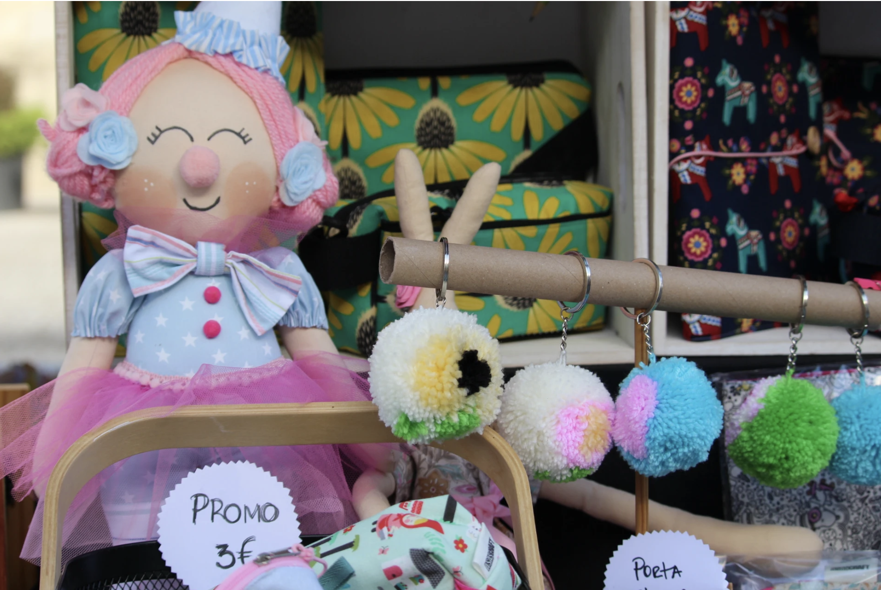 Boneca de tecido cor-de-rosa com vestido azul e pompons coloridos à venda