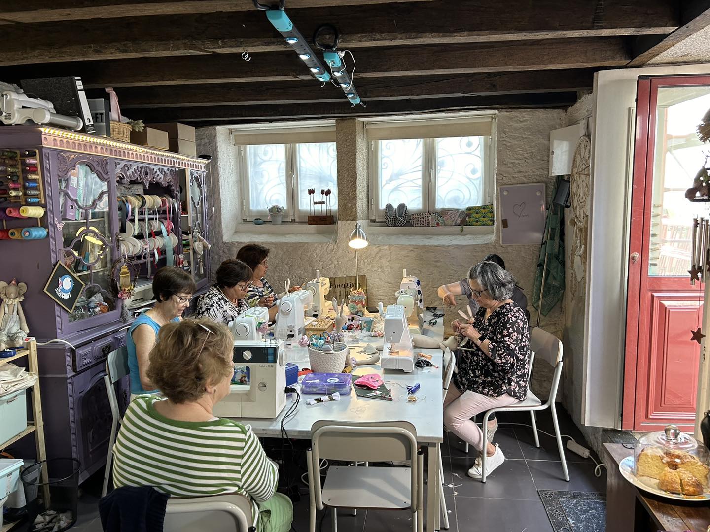 Mulheres costurando numa sala com máquina de costura e mesa branca
