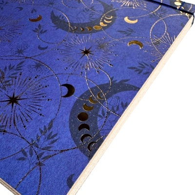 Caderno azul com decoração dourada de luas e estrelas