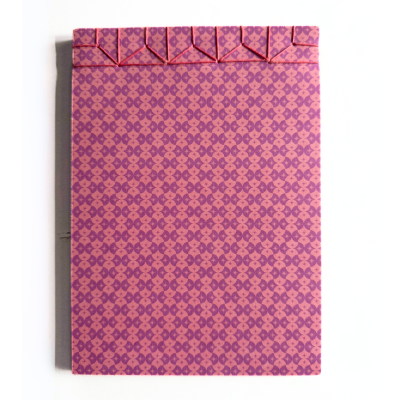 Caderno capa rígida com padrão geométrico rosa e roxo e costura vermelha