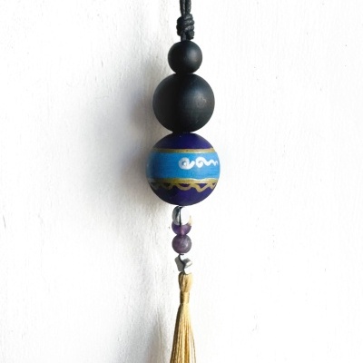 Pendurador decorativo com bolas de madeira pretas e azuis, contas e franja dourada