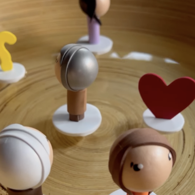 Mini figuras de bonecos coloridos em base branca sobre superfície de madeira