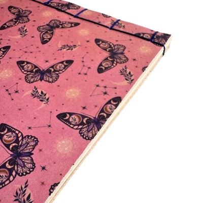 Caderno rosa com borboletas e constelações desenhadas.
