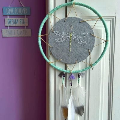 Apanhador de sonhos verde com bordado de libelinha e penas penduradas