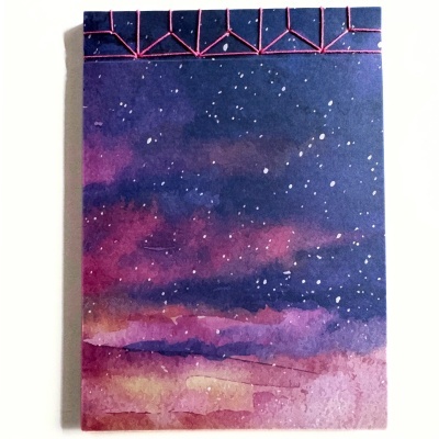 capa de caderno com padrão de céu estrelado em tons roxo, azul e rosa