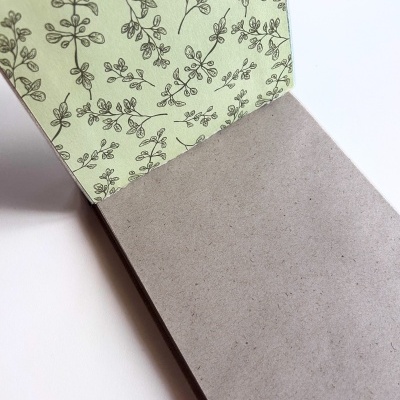 Bloco de anotações com capa floral verde e páginas cinzentas