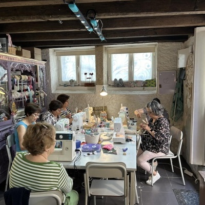 Mulheres costurando numa sala com máquina de costura e mesa branca